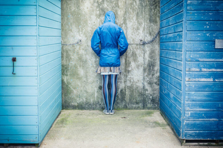 Person with head against the wall outside