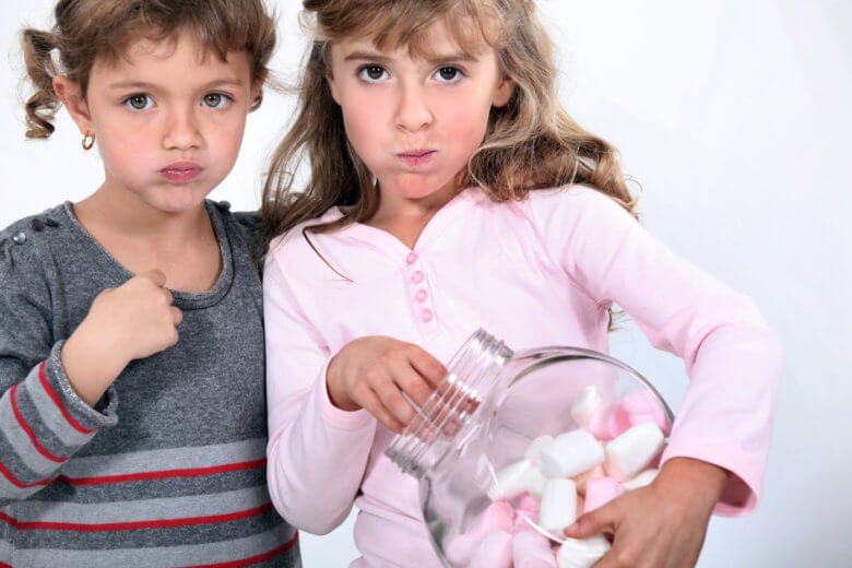 Two sisters eating marshmallows.